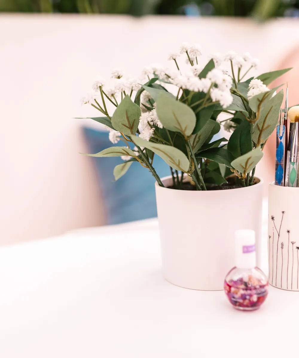 Plan de travail clair du salon avec pinceaux, flacon de vernis et fleurs