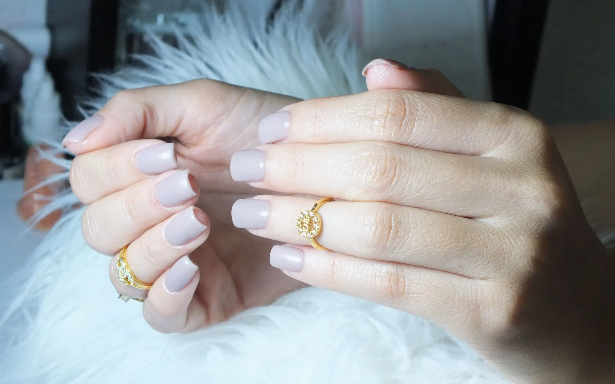 Mains aux ongles nude posées sur une fourrure blanche